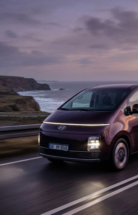Hyundai STARIA Electric kjører på en kystvei i solnedgang. Foto.