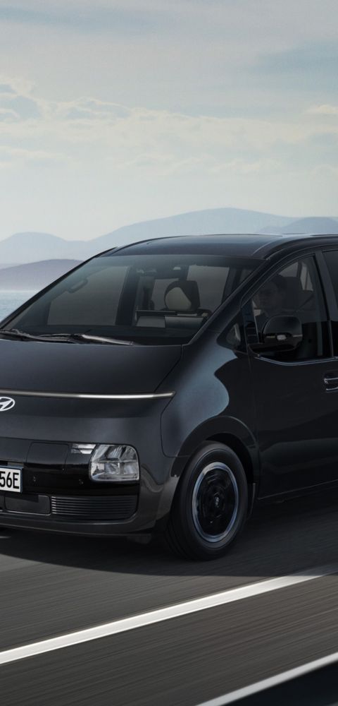 Side view of the Hyundai STARIA Electric in motion on a seaside highway