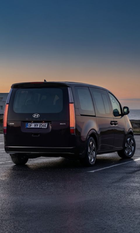Hyundai STARIA Electric viewed from the front, with a sunset in the background.