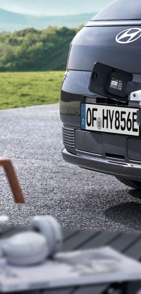 Hyundai STARIA Electric front charging port supplying power to an external device using Vehicle-to-Load (V2L) functionality.