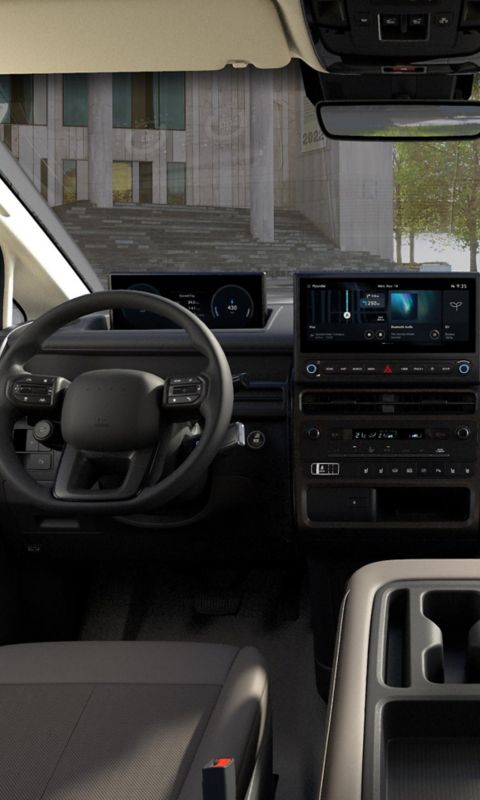 Front interior of the Hyundai STARIA Electric showing dashboard layout, dual screens, and multifunction steering wheel.