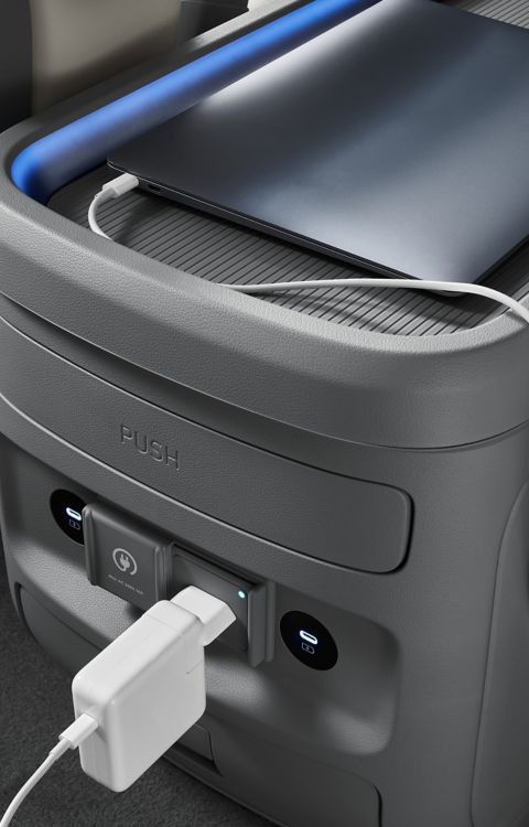 Hyundai STARIA Electric rear console with USB ports and power outlet charging a device.