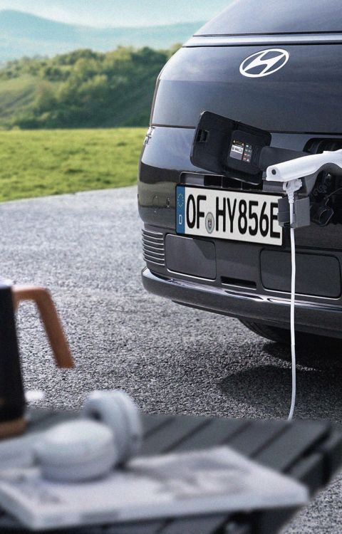 Hyundai STARIA Electric front charging port supplying power to an external device using Vehicle-to-Load (V2L) functionality.