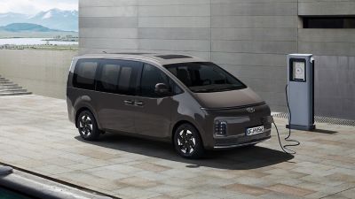 Hyundai STARIA Electric connected to an EV charger outdoors, highlighting convenient charging access.