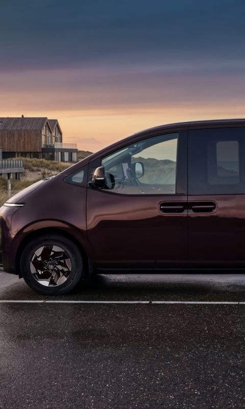 Hyundai i10 hatchback front three-quarter parked under a modern overhang with bold red and blue walls.