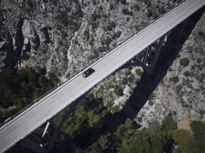 Hyundai SANTA FE rijdt over brug in bergachtige omgeving.