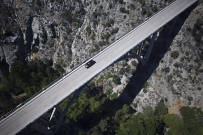Aus der Vogelperspektive gesehen, fährt ein Hyundai SANTA FE über eine Brücke, die über eine tiefe Schlucht führt.