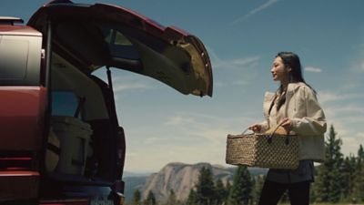 A woman carrying a basket walking toward the Hyundai Santa Fe.