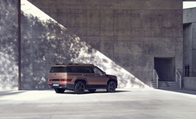 The Hyundai Santa Fe Hybrid parked in front of a high wall. 