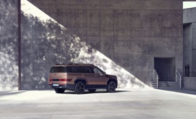 Hyundai SANTA FE geparkeerd voor een grote muur in de zon.