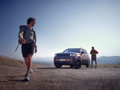 Two hikers walking away from the Hyundai Santa Fe with mountains in the background.