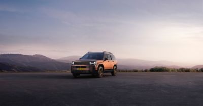 Driekwart vooraanzicht Hyundai SANTA FE, geparkeerd op plateau in bergachtig landschap..