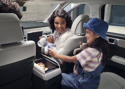 A child pulling a stuffed animal out of the multi-console storage space of the Hyundai Santa Fe.