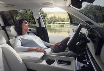 Eine Frau lehnt sich entspannt auf dem Fahrersitz des neuen Hyundai SANTA FE zurück.