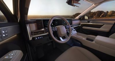 La vue intérieure éclairée du cockpit de Hyundai SANTA FE Nouvelle Génération au crépuscule.