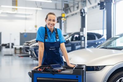 Woman works on a Hyundai car in the maintenance shop and supply the vehicle service. Background different Hyundai cars.