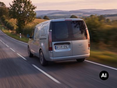 A rear view of Hyundai Cargo electric driving down the rural street.