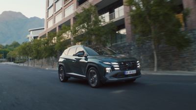 The Hyundai TUCSON Plug-in Hybrid is pictured from the side driving down the road. 