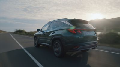 Pohľad zozadu zboku na Hyundai TUCSON Plug-in Hybrid jazdiaci po ceste. 