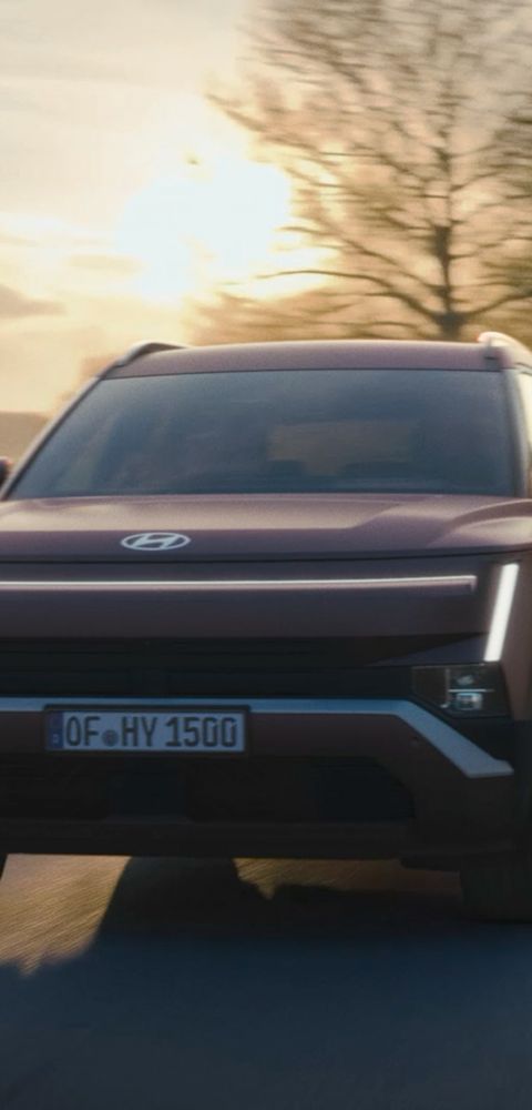 Hyundai TUCSON roulant le long d'une route avec le soleil se couchant en arrière-plan.