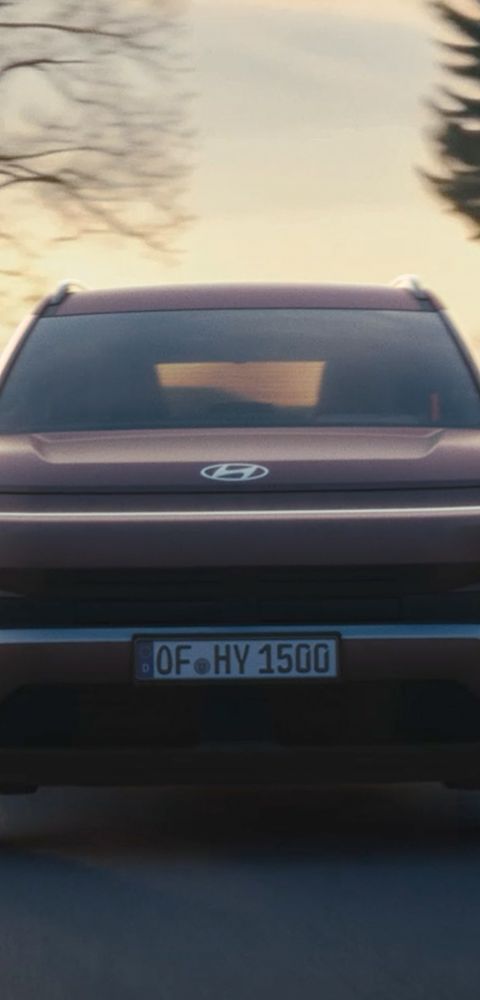 Hyundai TUCSON roulant sur une route à travers une zone boisée.