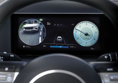 Cyfrowy zestaw wskaźników pokazujący lewą i prawą stronę za Hyundaiem TUCSON Hybrid. 
