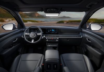 Inside view of the Hyundai TUCSON Hybrid dashboard, steering wheel, mirrors, with seaside panorama.