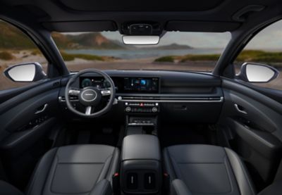 Inside view of the Hyundai TUCSON Hybrid dashboard, steering wheel, mirrors, with seaside panorama.