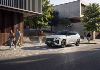 The Hyundai TUCSON Plug-in Hybrid parked in front of a house with trees. 