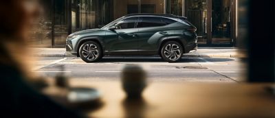 Şehir içinde bir caddeye park edilmiş Hyundai TUCSON Hibrit.