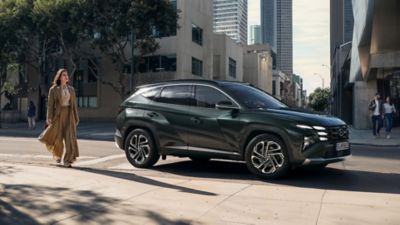 Hyundai TUCSON Plug-in Hybrid büyük bir bina önünde park halinde.