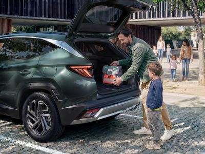 Muž a dítě nakládající zavazadla do prostorného zavazadlového prostoru vozu Hyundai TUCSON .