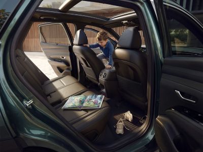 Interiér modelu TUCSON  a dítě prolezající přes sedačky.