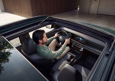 Pohled přes otevřenou panoramatickou střechu na muže sedící za volantem modelu TUCSON.