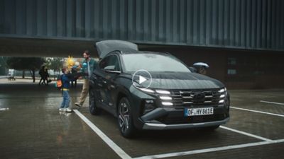 A man and a child loading items into the spacious trunk of a Hyundai Tucson Plug-in Hybrid	.