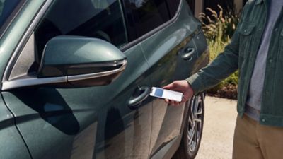 Muž odemykající dveře řidiče vozu Hyundai TUCSON  pomocí digitálního klíče Hyundai.