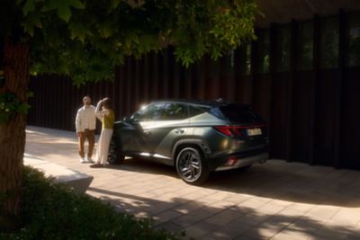 A man and a woman leaning on the bonnet of the Hyundai TUCSON 20th Anniversary Edition.	