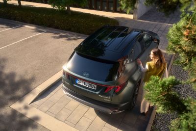 Hyundai TUCSON 20th Anniversary Edition seen from above with a woman touching the side.	