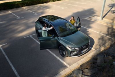 A man and a woman getting into the front seats of the Hyundai TUCSON 20th Anniversary Edition.	