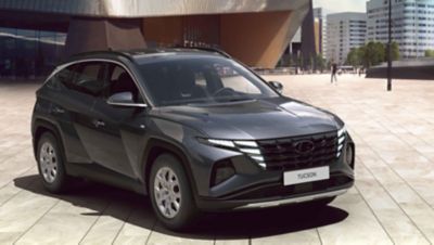 Imagen del nuevo Hyundai TUCSON aparcado frente a los edificios de una ciudad.
