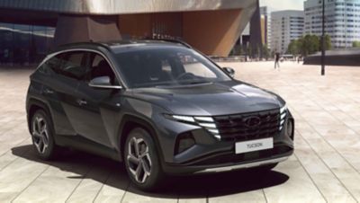 Man walking by the all-new Hyundai TUCSON Hybrid N Line between windmills.