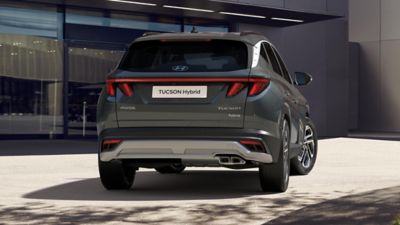 The Hyundai TUCSON Plug-in Hybrid is seen from the side back driving down the road.