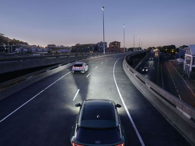 Der Hyundai TUCSON fährt bei Nacht über eine Brücke mit eingeschalteten Matrix-LED-Scheinwerfern.