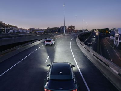 Le Hyundai TUCSON Hybrid vu d'en haut alors qu'il roule dans l'obscurité avec les phares allumés.