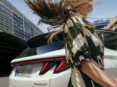 Kobieta przechodząca za Hyundaiem TUCSON. 