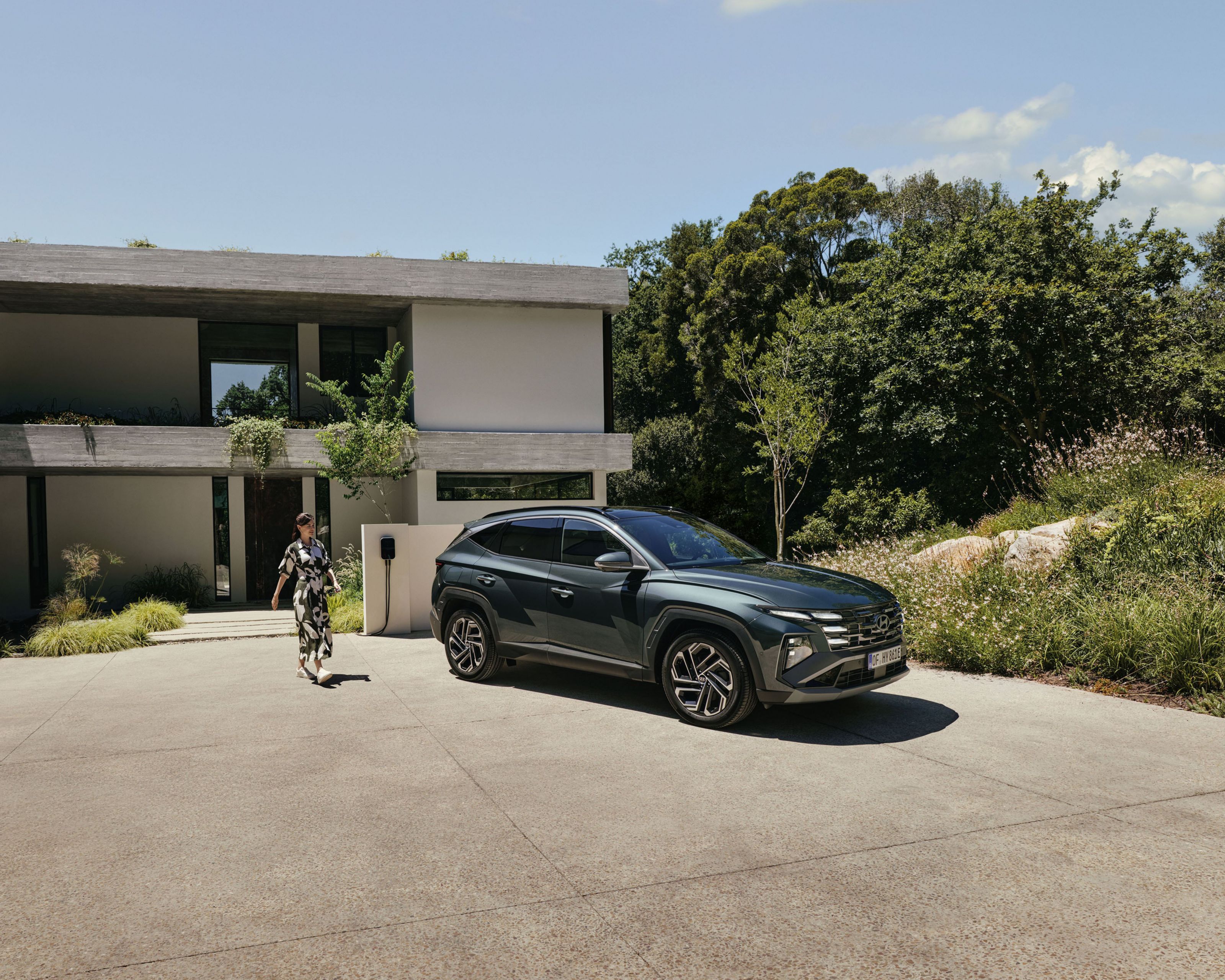 The Hyundai TUCSON Plug-in Hybrid parked in front of a big house.