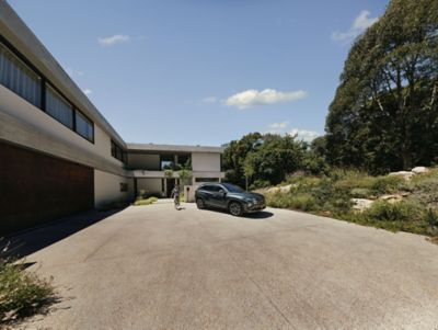 Zijaanzicht geparkeerde Hyundai TUCSON voor modern gebouw met vrouw links ernaast.