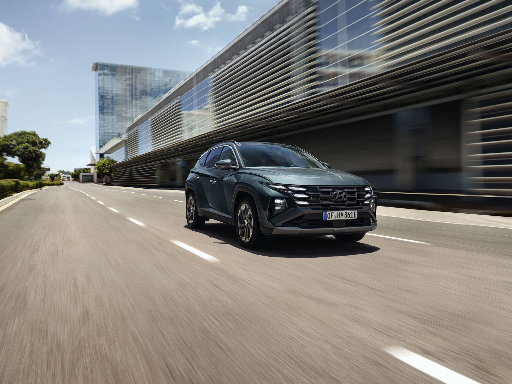 The Hyundai TUCSON Plug-in Hybrid driving down a city street with modern buildings visible.