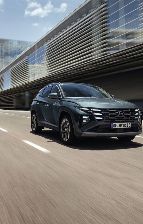 El Hyundai TUCSON circulando por una calle de la ciudad, con edificios modernos a la vista.