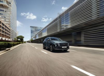 Rijdende Hyundai TUCSON in het midden van een rijstrook van een geasfalteerde weg.